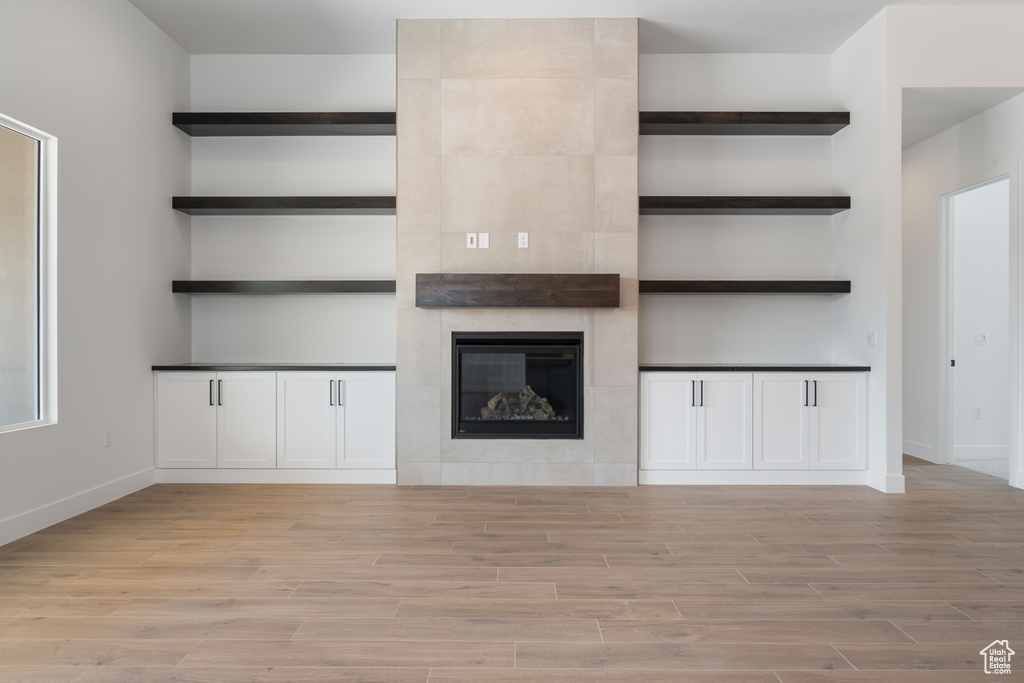Unfurnished living room featuring light wood-style floors, baseboards, and a fireplace