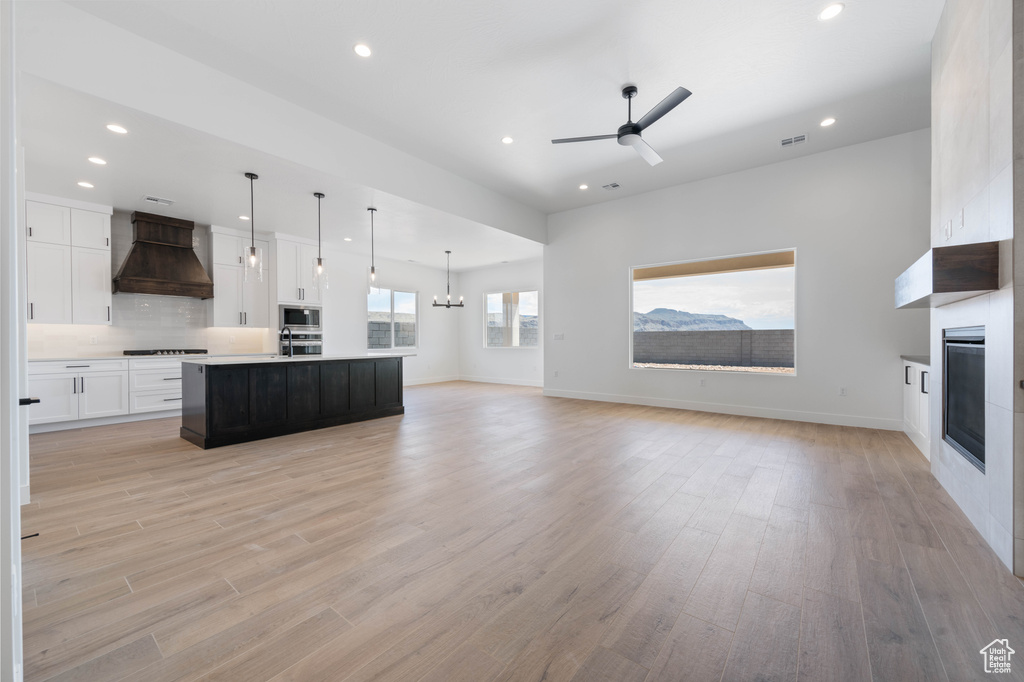 Kitchen with open floor plan, appliances with stainless steel finishes, custom range hood, a fireplace, and recessed lighting