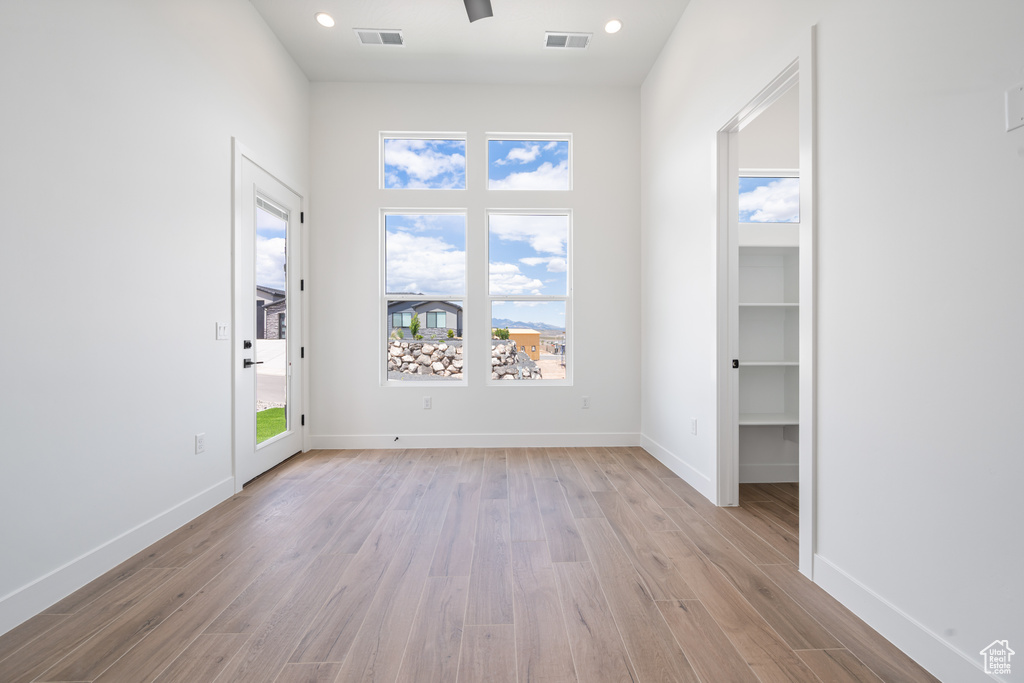 Unfurnished room with light wood finished floors, baseboards, and recessed lighting