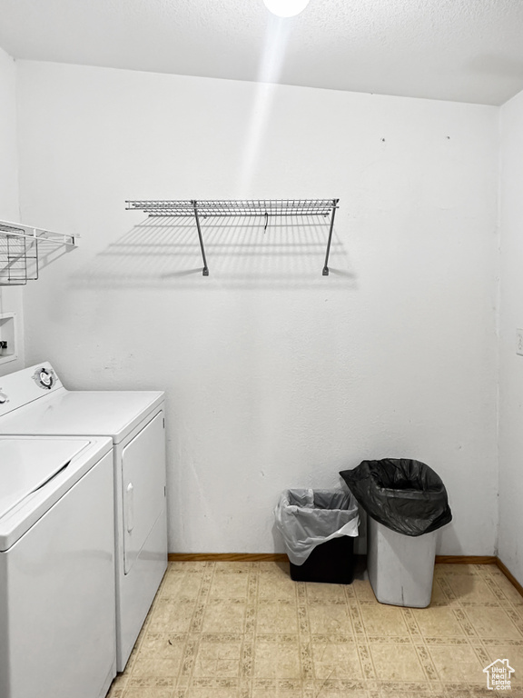 Washroom with washing machine and dryer, light flooring, and baseboards