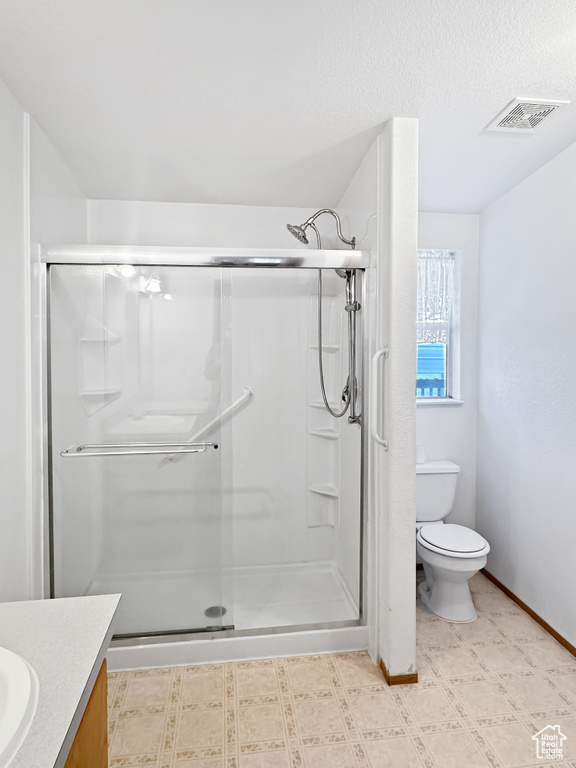 Full bath featuring toilet, vanity, a shower stall, baseboards, and tile patterned floors