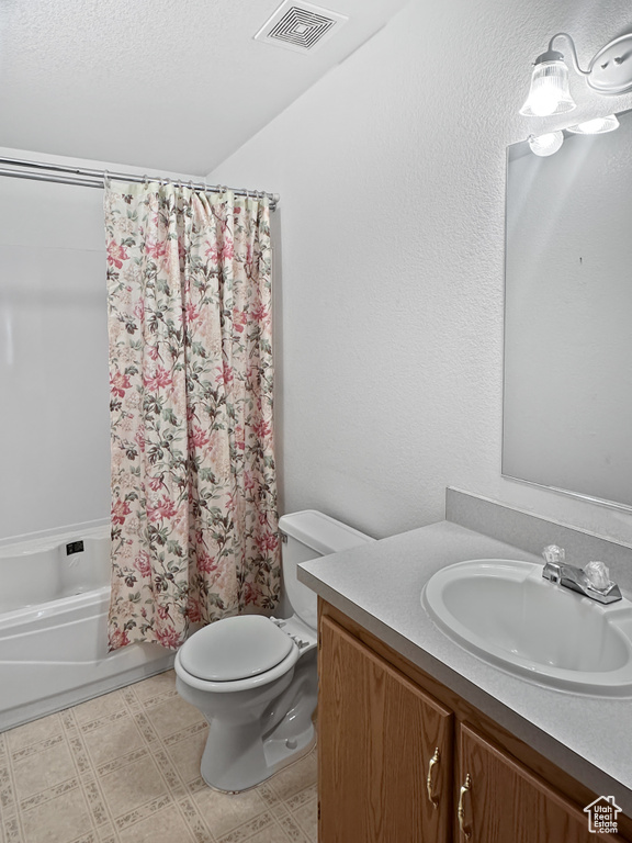 Bathroom featuring toilet, vanity, shower / bath combination with curtain, and a textured ceiling