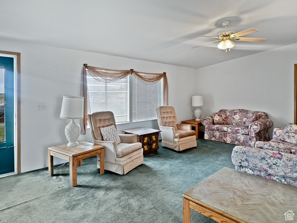 Carpeted living area featuring ceiling fan
