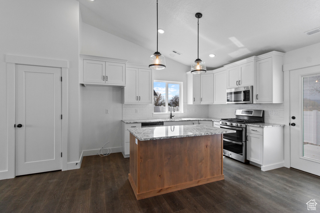 Kitchen with appliances with stainless steel finishes, backsplash, white cabinetry, lofted ceiling, and recessed lighting
