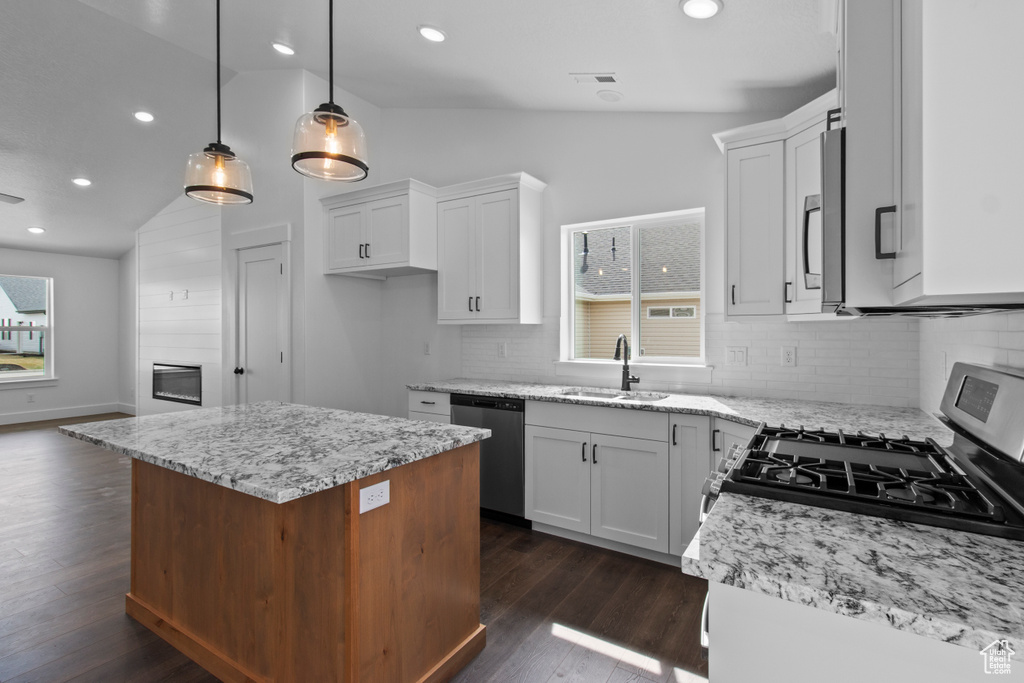 Kitchen with a sink, appliances with stainless steel finishes, lofted ceiling, recessed lighting, and white cabinets