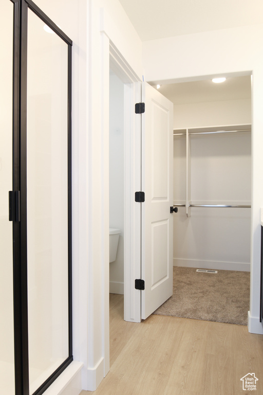 Hall with light wood-type flooring, baseboards, and light colored carpet