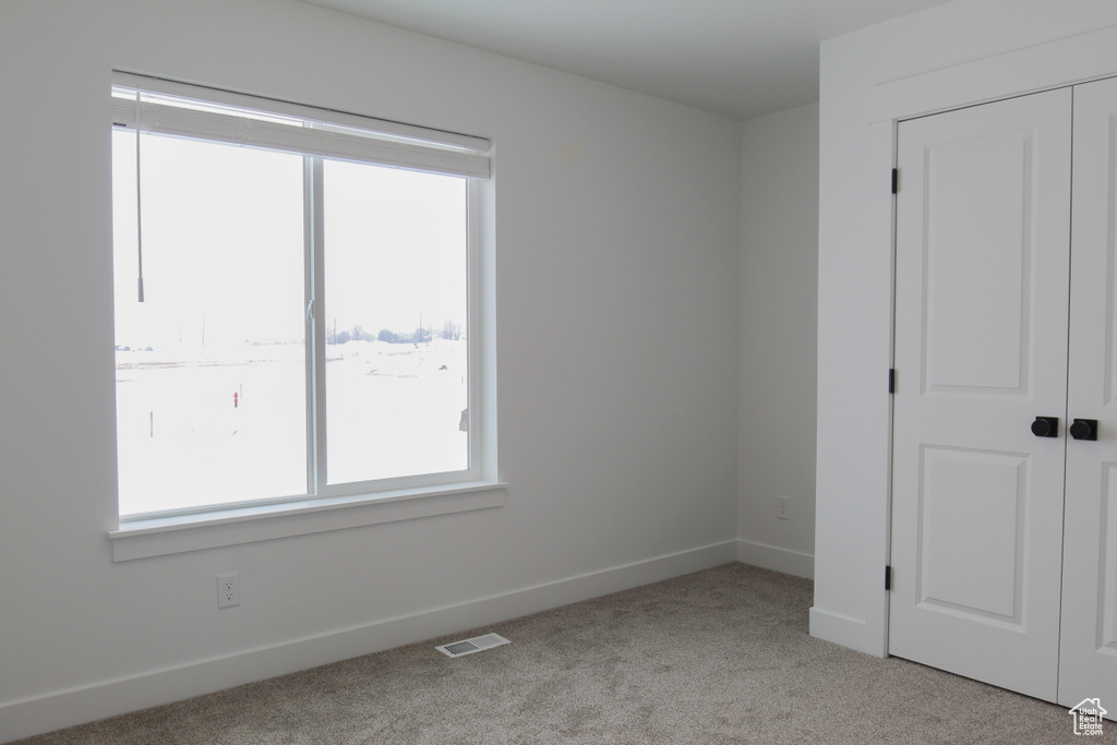Unfurnished bedroom with light carpet, baseboards, and a closet