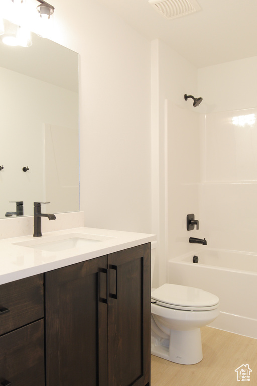 Full bath featuring wood finished floors, toilet, vanity, and bathtub / shower combination