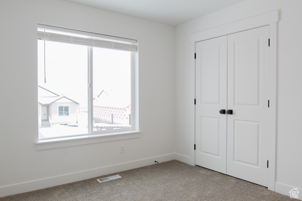 Unfurnished bedroom with carpet floors, a closet, and baseboards