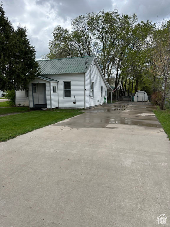 View of front of house featuring concrete driveway, metal roof, and a front yard