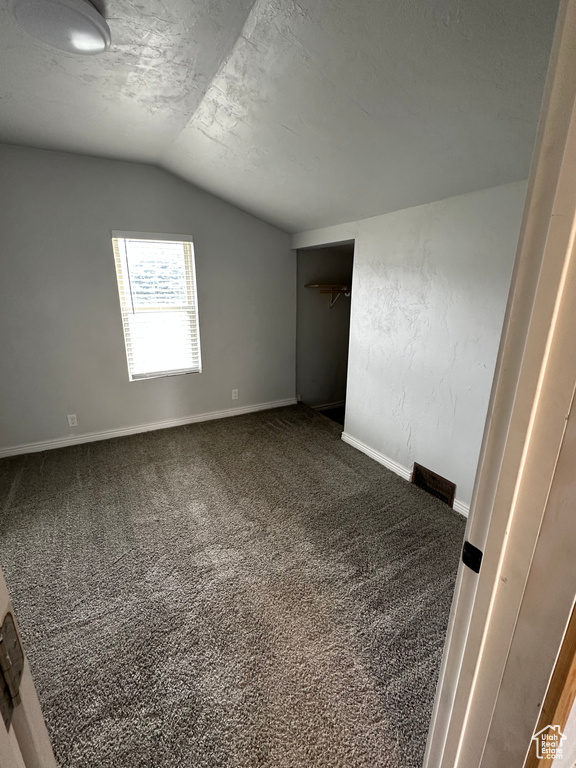Spare room featuring lofted ceiling, carpet, and baseboards