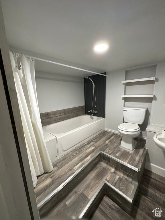 Full bath with toilet, a tub, baseboards, and wood finished floors