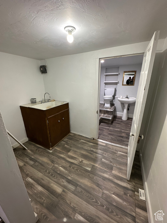 Bathroom with a sink, toilet, wood finished floors, a textured ceiling, and baseboards