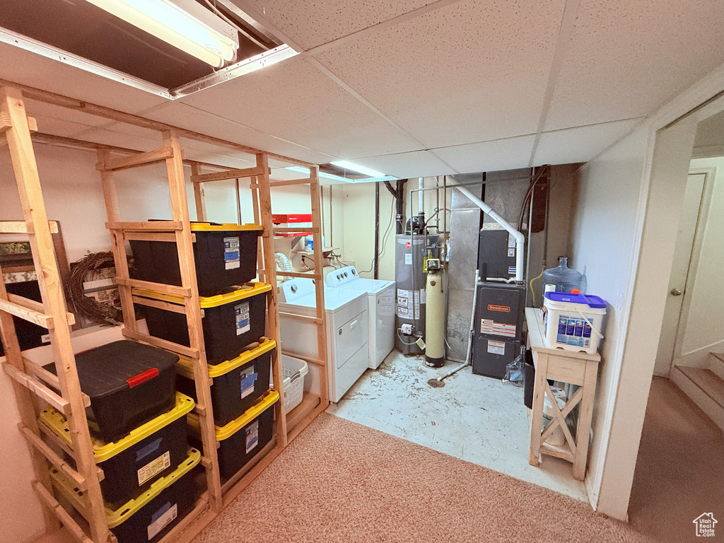 Finished below grade area featuring separate washer and dryer, water heater, heating unit, and stairs