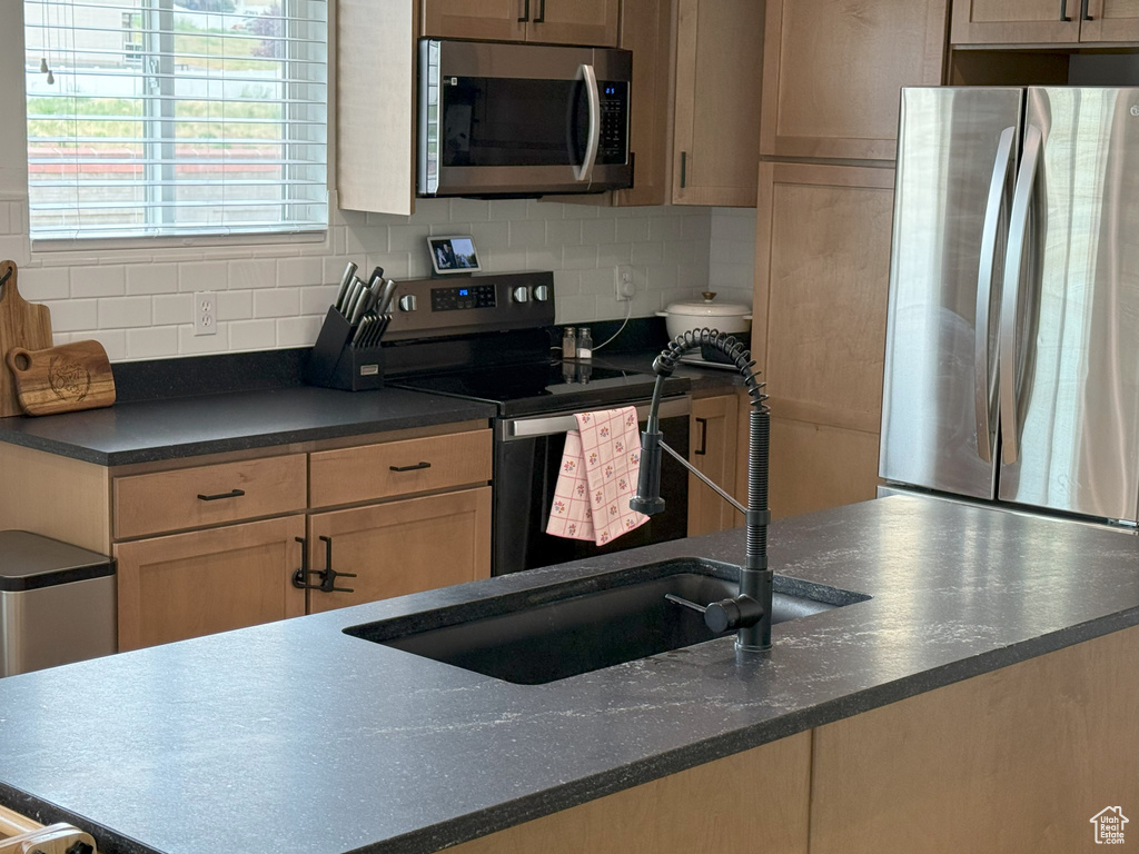Kitchen with stainless steel appliances and tasteful backsplash