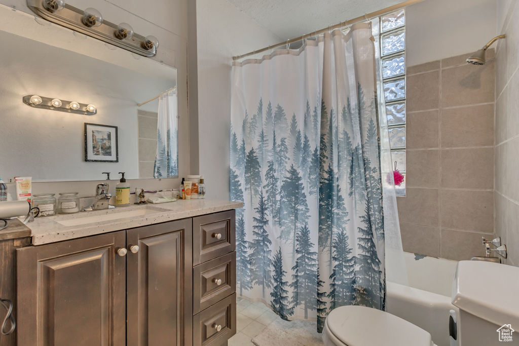 Bathroom with toilet, shower / bath combo with shower curtain, vanity, and tile patterned floors