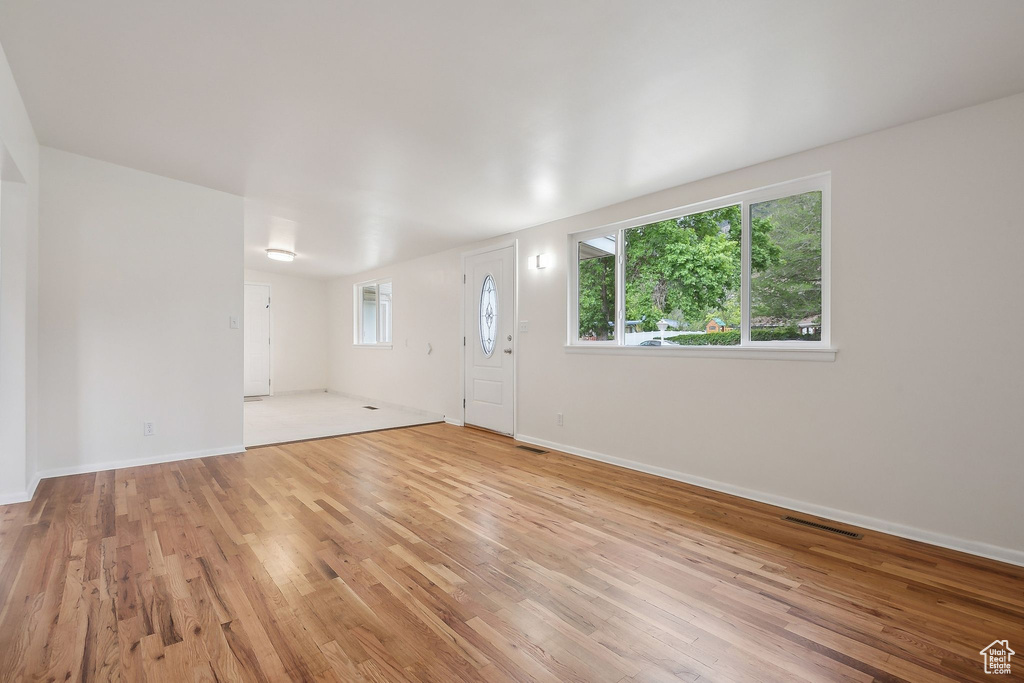 Unfurnished living room with light wood finished floors, plenty of natural light, and baseboards
