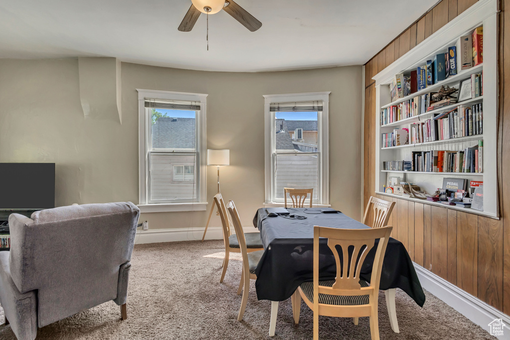 Carpeted dining space with ceiling fan, plenty of natural light, and baseboards