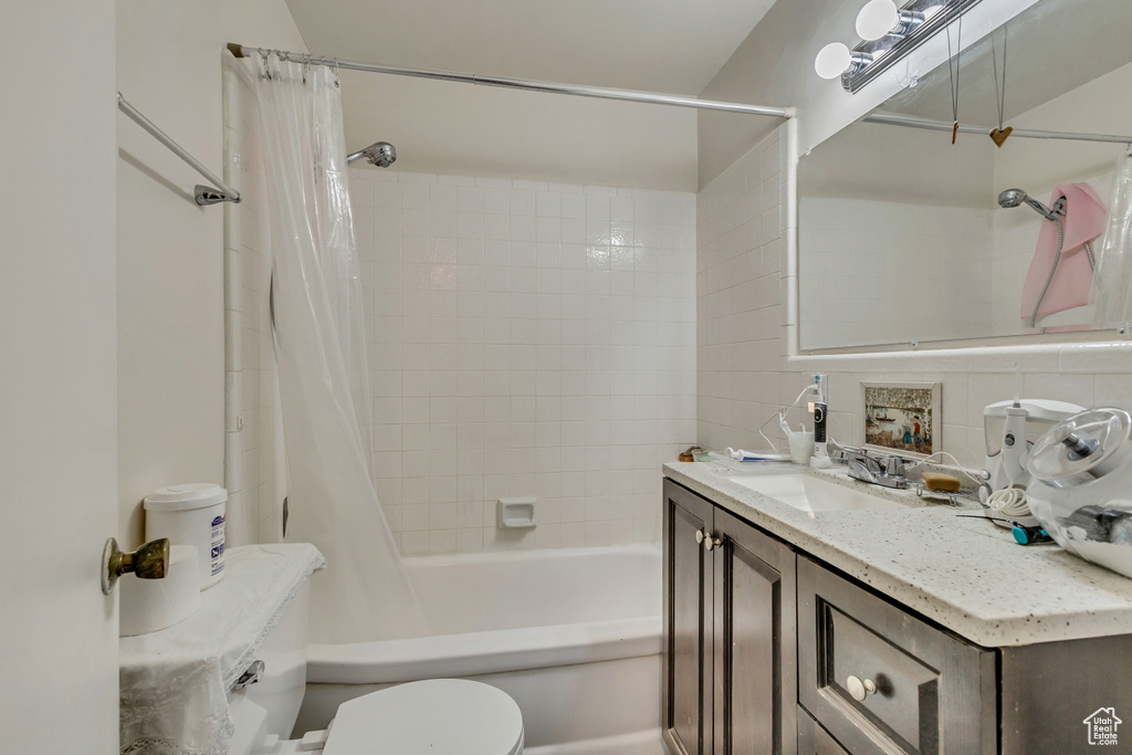 Bathroom featuring toilet, shower / bath combination with curtain, and vanity