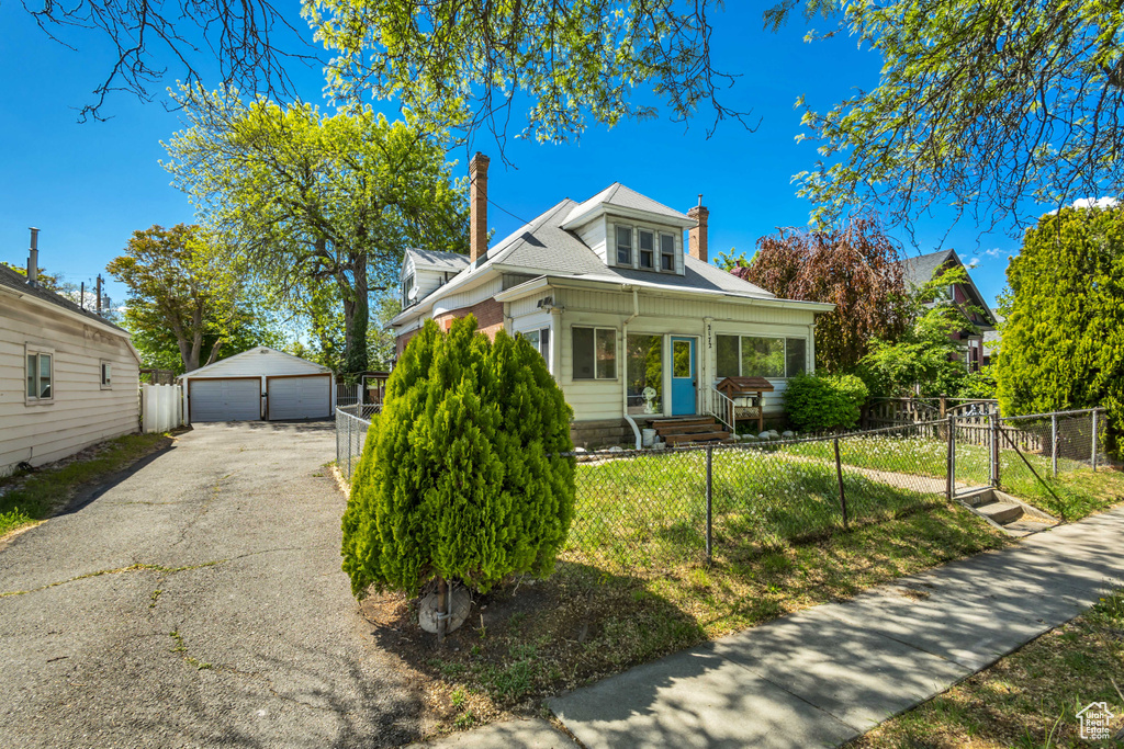 Bungalow with a garage, a chimney, a fenced front yard, an outdoor structure, and a gate