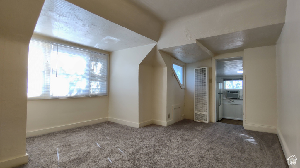 Additional living space with a heating unit, carpet floors, and baseboards