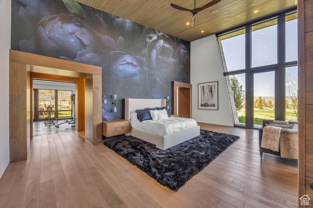 Bedroom with a towering ceiling, wood-type flooring, wood ceiling, recessed lighting, and expansive windows