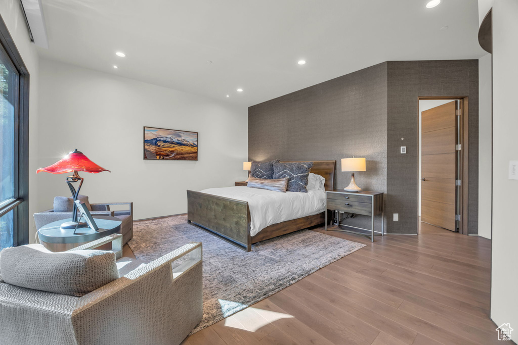 Bedroom with recessed lighting, wood finished floors, and an accent wall