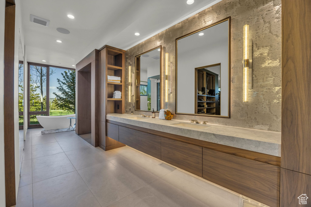 Full bath featuring recessed lighting, double vanity, a freestanding tub, and floor to ceiling windows