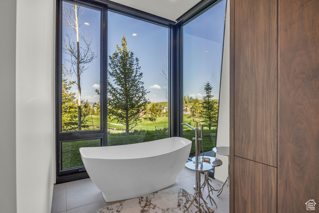 Bathroom featuring floor to ceiling windows, a freestanding bath, and tile patterned floors