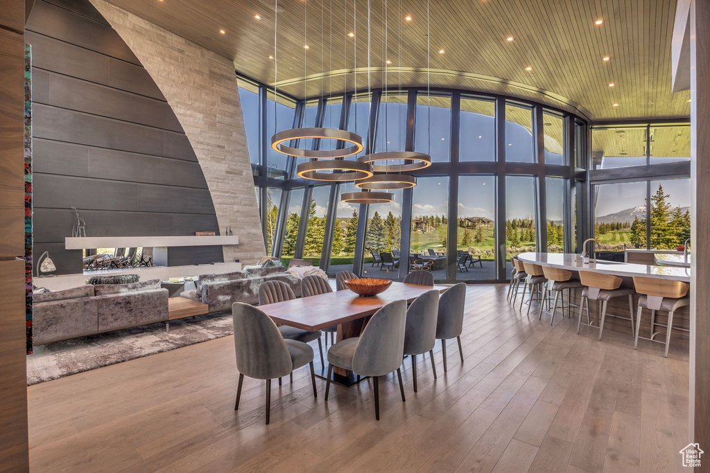 Dining area with expansive windows, a high ceiling, healthy amount of natural light, and hardwood / wood-style flooring