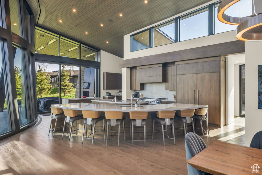 Kitchen featuring a towering ceiling, light countertops, a spacious island, wood finished floors, and modern cabinets