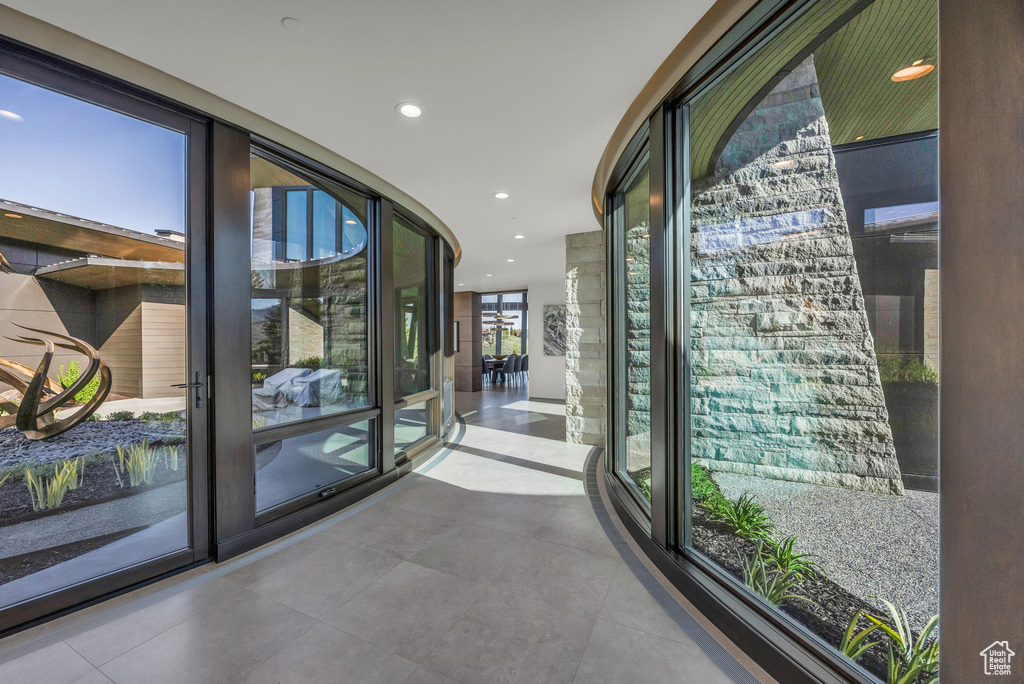 Hall featuring a wall of windows, tile patterned floors, and recessed lighting