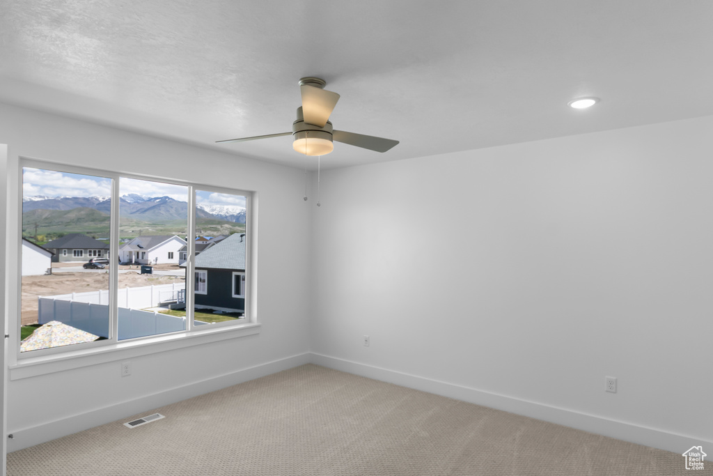 Unfurnished room featuring ceiling fan, baseboards, light colored carpet, recessed lighting, and a mountain view