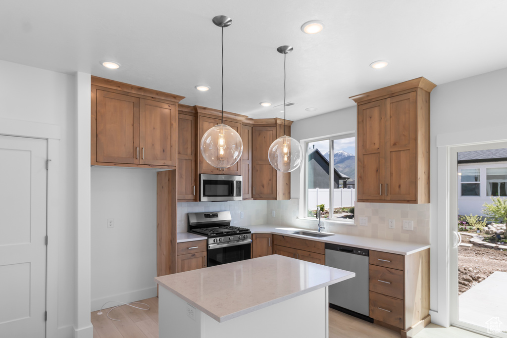 Kitchen with stainless steel appliances, a sink, tasteful backsplash, light wood-style floors, and recessed lighting