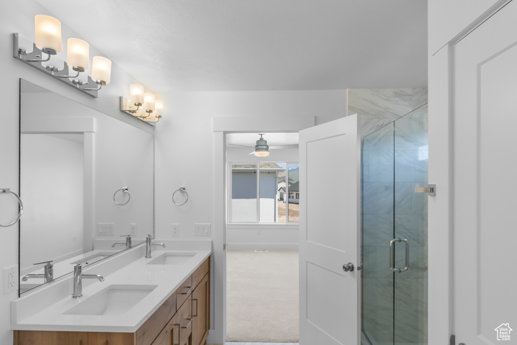 Bathroom featuring a ceiling fan, a shower stall, and double vanity