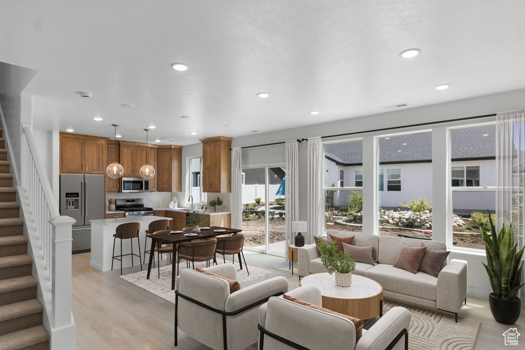 Living room with light wood-type flooring, stairs, and recessed lighting