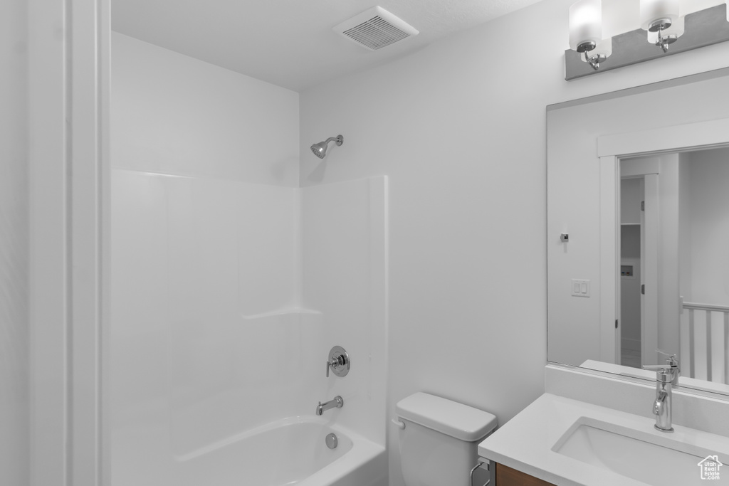 Bathroom featuring toilet, shower / bathtub combination, and vanity