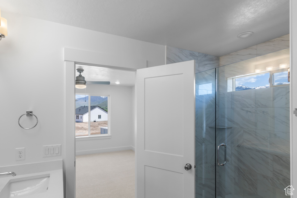 Bathroom with plenty of natural light, a stall shower, a sink, and a ceiling fan