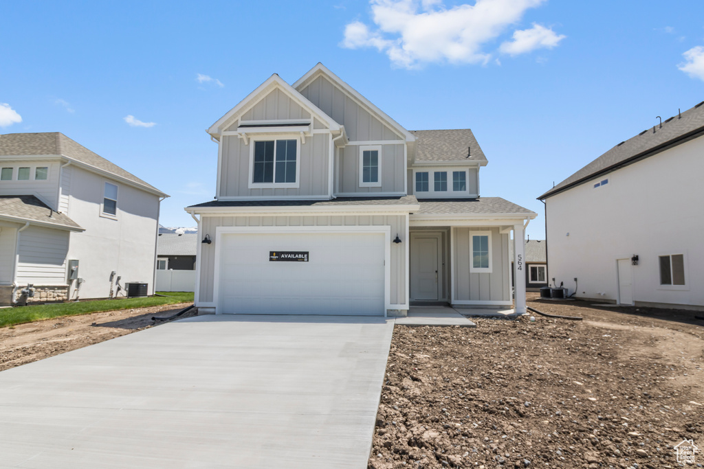 View of front of house with board and batten siding, central air condition unit, concrete driveway, a garage, and roof with shingles