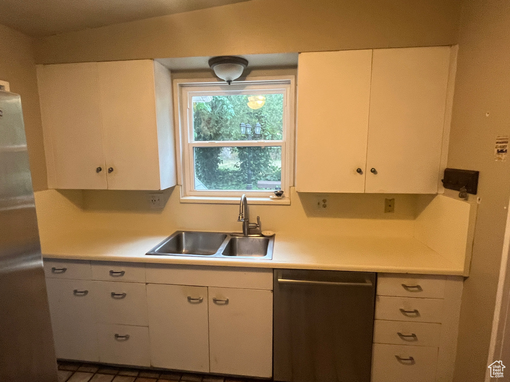 Kitchen with dishwasher, a sink, light countertops, and white cabinetry