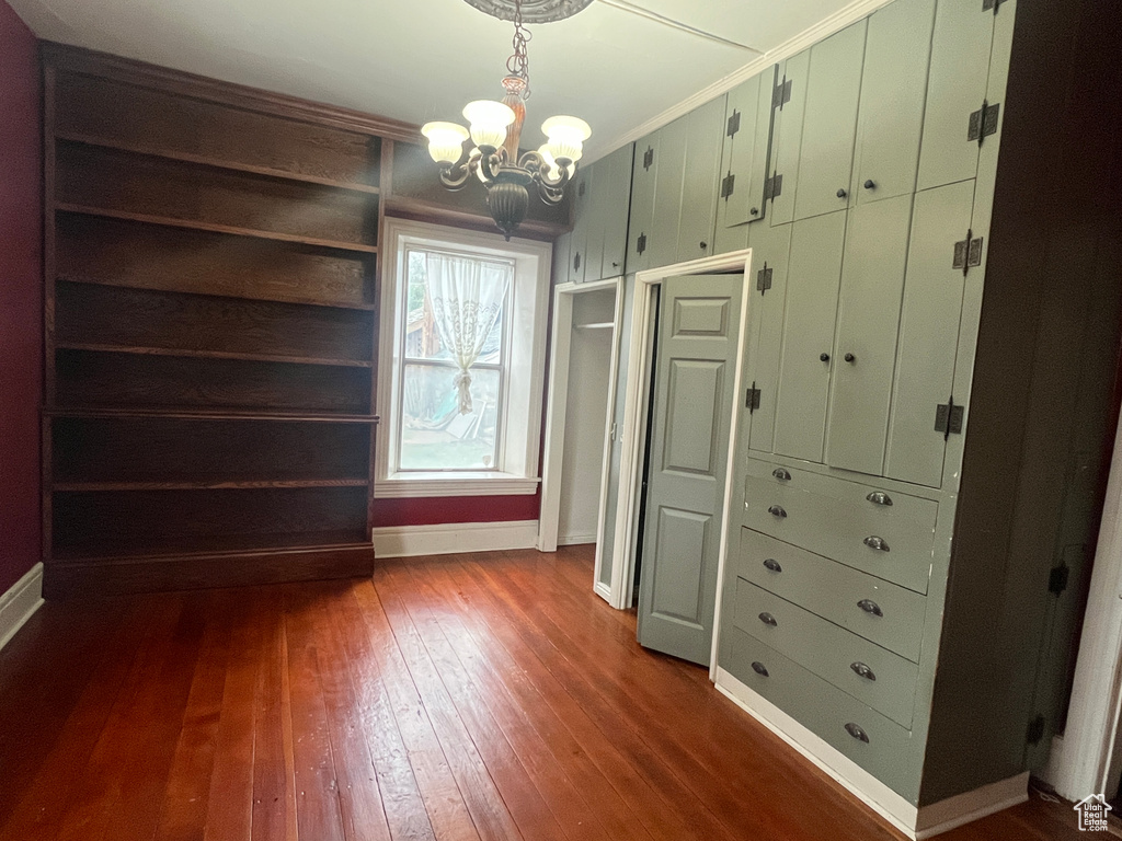 Walk in closet with a chandelier and dark wood finished floors