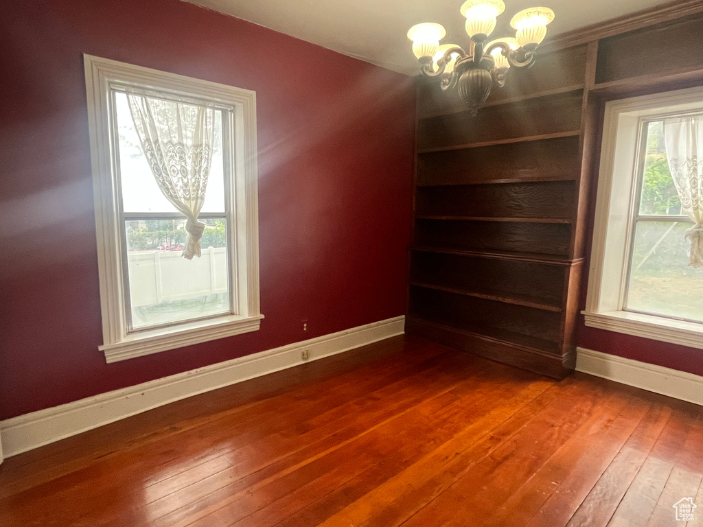 Unfurnished dining area featuring baseboards, wood-type flooring, and a chandelier
