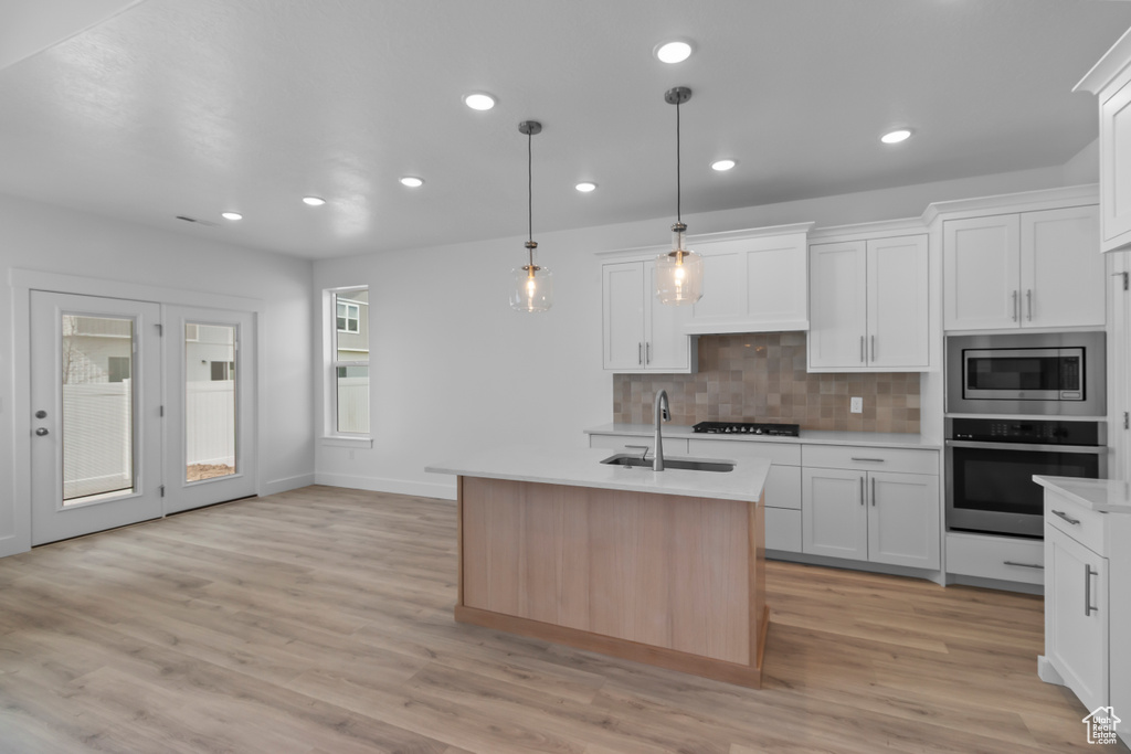 Kitchen featuring appliances with stainless steel finishes, a sink, light countertops, backsplash, and recessed lighting