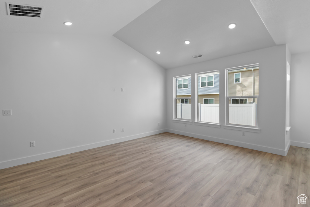 Spare room featuring light wood-style flooring, baseboards, vaulted ceiling, and recessed lighting