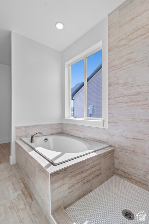 Bathroom featuring a bath and a tile shower