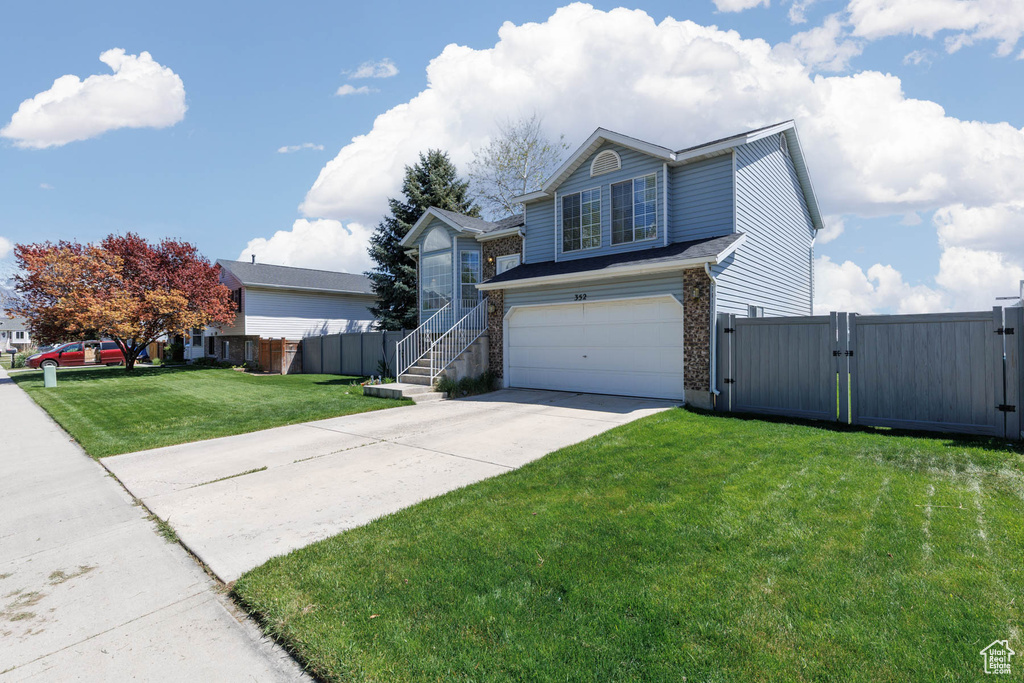 Traditional-style home featuring a gate, an attached garage, and concrete driveway