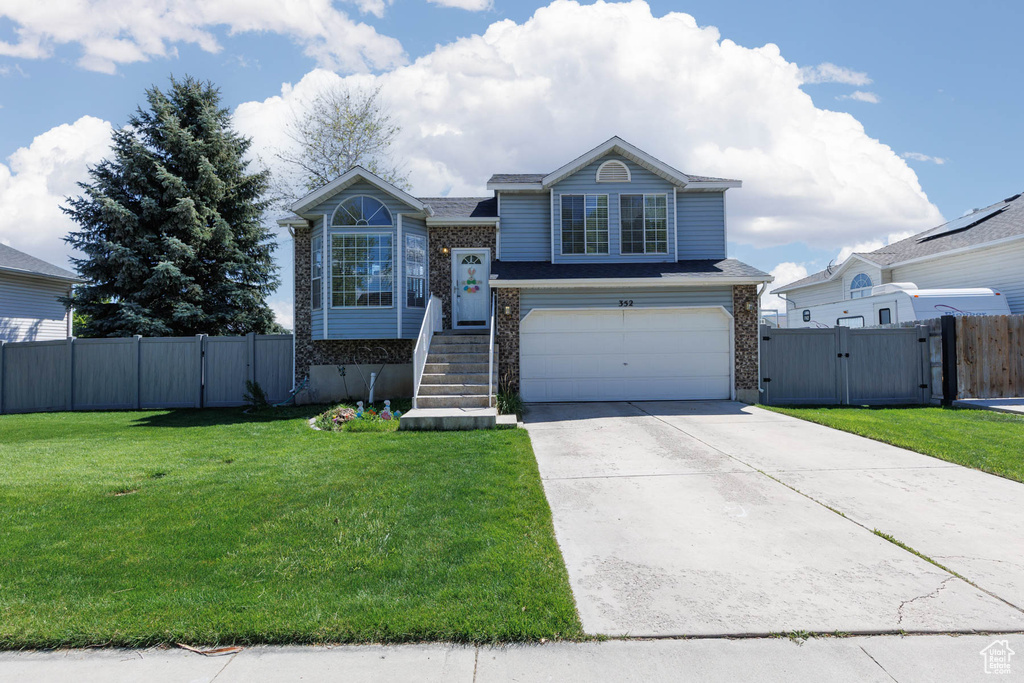 View of front of property featuring a gate, a garage, concrete driveway, and brick siding