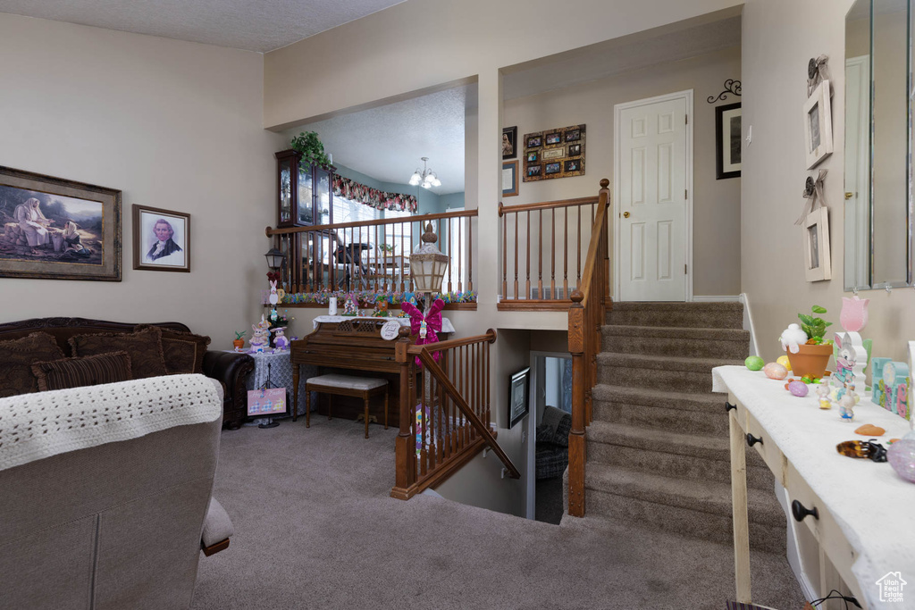 Carpeted living area with a chandelier and stairs