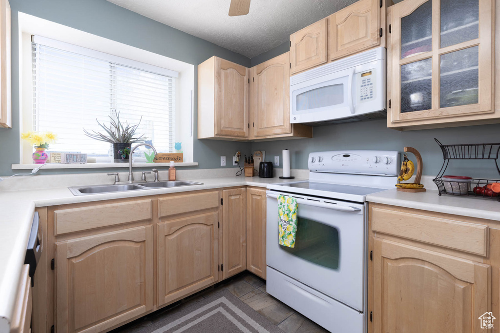 Kitchen with white appliances, a sink, light brown cabinetry, light countertops, and a textured ceiling