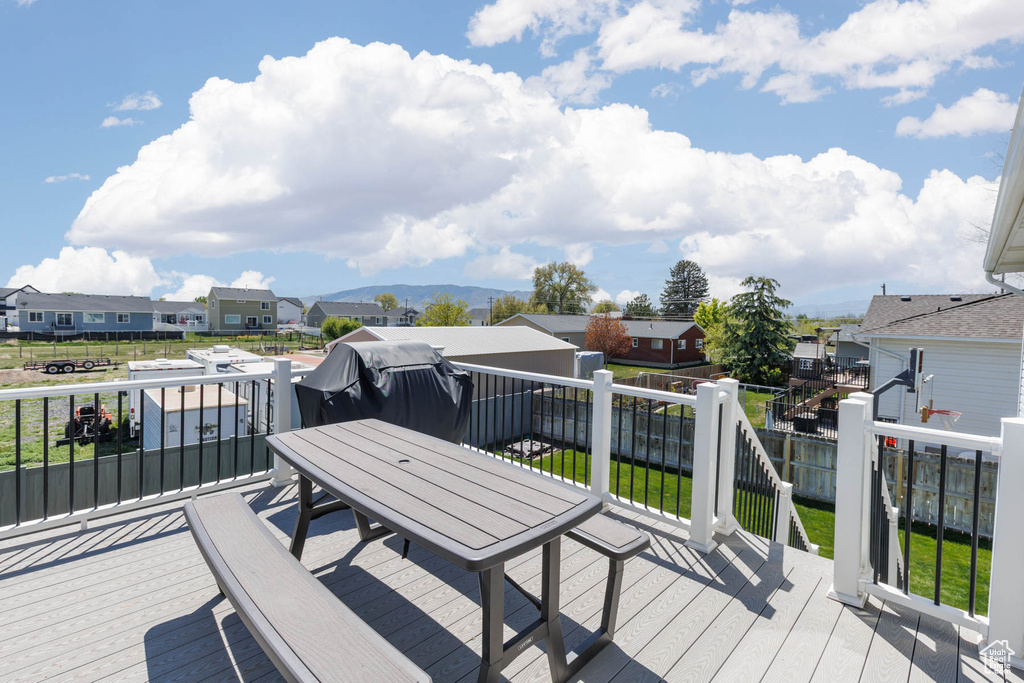 Wooden terrace featuring a residential view, outdoor dining space, and fence